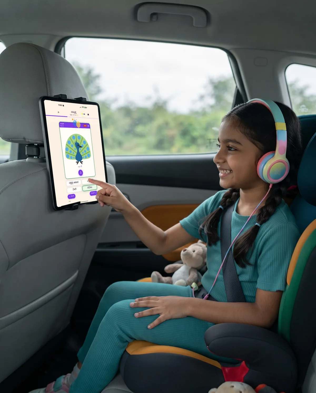 A child practising with Aksharamaala on a tablet during a car journey